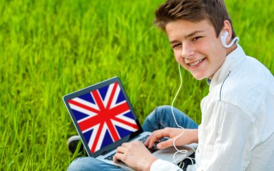 Portrait of attractive teen boy learning english on laptop outdoors.